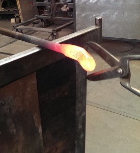 metal scissors cutting a blob of molten glass on a rod