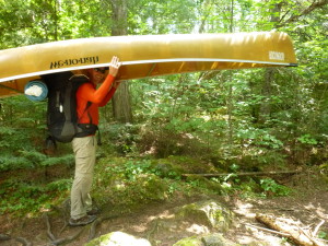 man in the BWCA carrying canoe and backpack in forest