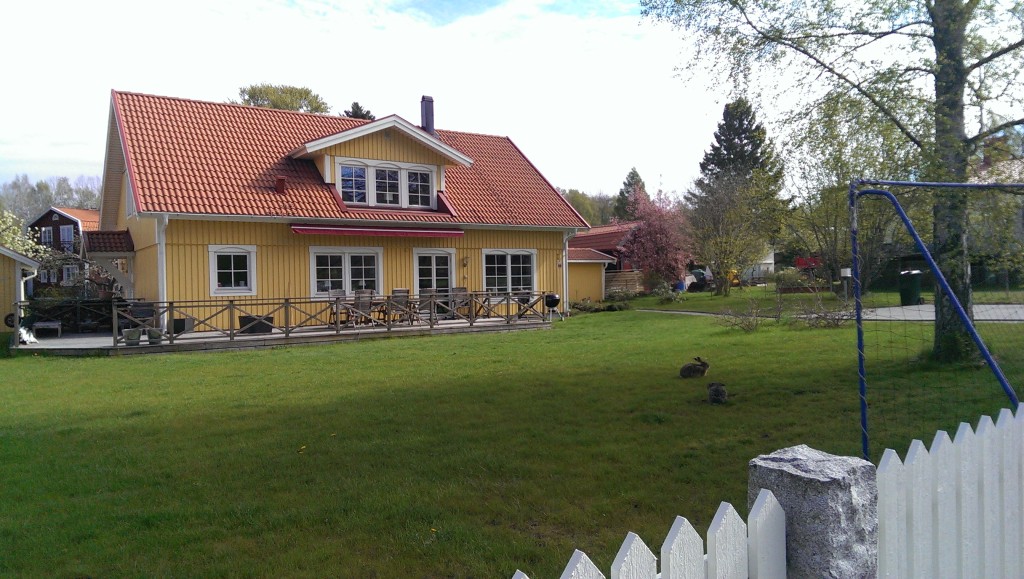 yellow swedish house with lawn and white picket fence