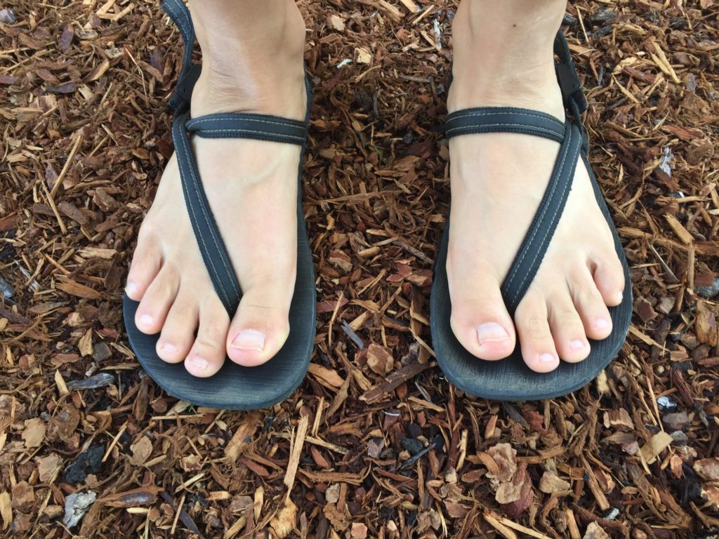 earth runners elemental barefoot running sandals being worn by a barefoot runner standing on a trail